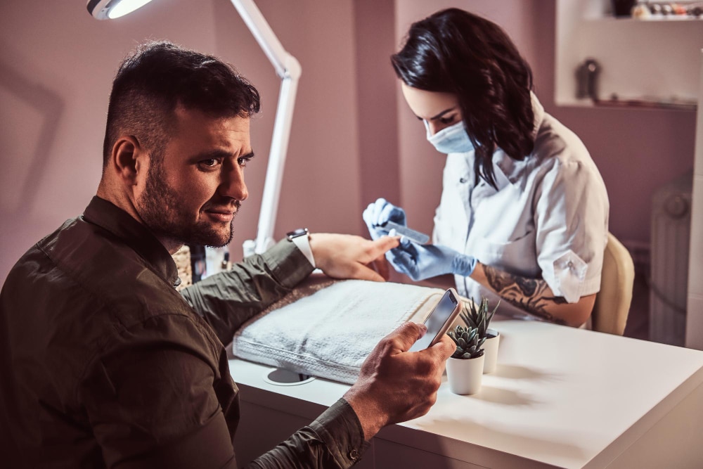 Image of nail tech doing manicure to a man 